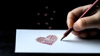 Hand drawing red heart shape on white paper with small floating hearts against dark background. Romantic concept for Valentine's day cards and love messages.