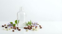 Clear glass bottle with lavender flowers and coffee beans on white background for natural cosmetics and aromatherapy products.