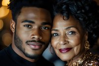 African American young man and senior woman smiling together in warm portrait with golden bokeh lights background for family celebration moments.