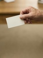 Senior adult male hand holding blank white card for voting, business card mockup, or promotional message display.