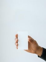 Male hand holding blank white card against neutral background for branding, business card mockup, or promotional material display.