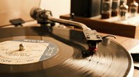 Vintage turntable with vinyl record playing, retro audio equipment setup for music production and DJ mixing in warm studio lighting atmosphere.