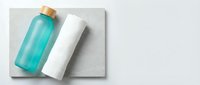 Turquoise and white cosmetic bottles with cork caps on gray textured surface, isolated for skincare, beauty product packaging design.
