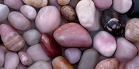 Collection of polished gemstones and healing crystals in pink, brown and neutral tones arranged together for meditation, wellness and spiritual practices.