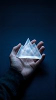 Hand holding transparent glass iceberg against dark blue background, symbolizing hidden potential, climate change awareness, or environmental concepts for business and sustainability messaging.