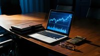 Business laptop displaying financial charts and market data on wooden desk with notebook, glasses and calculator for trading analysis.