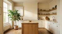 Bright farmhouse kitchen with cream cabinetry, wooden island, open shelving, potted plant by window, and warm natural lighting for home design and interior decoration projects.