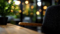 Cozy home interior with modern gray armchair and wooden table against blurred bokeh lights background, creating warm atmospheric mood.