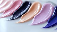Cosmetic foundation or concealer swatches in different skin tones and colors. Creamy texture makeup samples showing product consistency on white background.