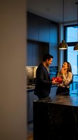 Happy couple exchanging gift in modern luxury kitchen with marble countertops and pendant lighting during romantic evening celebration at home.