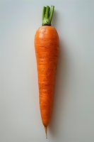 Fresh orange carrot with green leaves isolated on white background. Natural organic vegetable showing texture and detail in minimalist composition.