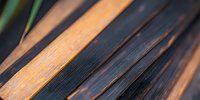 Diagonal pattern of contrasting burnt and natural wood planks creating modern rustic texture, suitable for interior design and architectural backgrounds.
