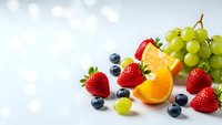 Fresh mixed fruits including strawberries, blueberries, grapes and orange slices arranged on white background for healthy eating and nutrition concepts.