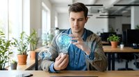Young businessman holding glowing lightbulb with digital network connections in modern office workspace representing innovation and creative thinking.
