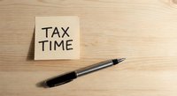 Sticky note with tax time text and black pen on wooden desk surface for accounting and financial planning preparation during filing season.