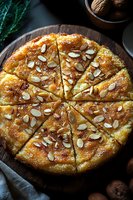 Sliced almond cake with caramelized sugar topping on wooden board, garnished with toasted sliced almonds and served with walnuts for dessert menu.