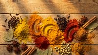 Colorful spices and herbs arranged on rustic wooden background with cinnamon sticks, star anise, bay leaves creating vibrant culinary display for cooking.