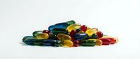 Colorful gel capsules and pills scattered on white background, pharmaceutical supplements and vitamins for health and wellness concepts.