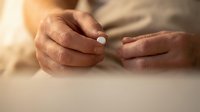 Senior hands holding white pill medication tablet for health treatment and daily wellness routine.