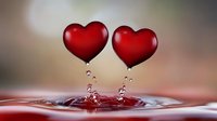 Red heart-shaped water drops creating splash ripples on liquid surface with bokeh background, romantic macro photography for Valentine's day and love concepts.