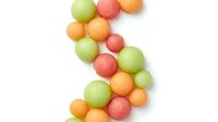Colorful round candies in green, orange and pink scattered on white background isolated for confectionery design and sweet treat marketing materials.