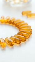 Golden omega-3 fish oil capsules arranged in curved line on white surface for health and wellness supplement marketing materials.