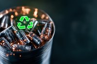Green recycling symbol glowing above glass container filled with used batteries, highlighting environmental responsibility and e-waste management.