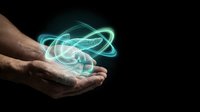 Hands holding glowing atomic structure with orbiting electrons on dark background. Science technology concept for education, research and innovation presentations.