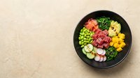 Colorful fresh vegetables and diced meat arranged in black bowl on beige surface, overhead view for healthy eating, meal prep, and nutrition content.