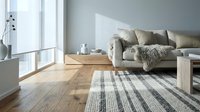 Modern Scandinavian living room interior with gray sofa, wooden coffee table, striped rug and natural light from large windows creating cozy atmosphere.