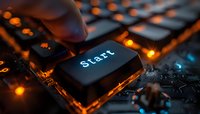 Illuminated start key on computer keyboard with orange backlight and bokeh effects creating atmospheric technology mood for business concepts.