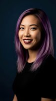 Young Asian woman with vibrant purple hair smiling confidently in professional portrait against dark blue background for business and lifestyle content.