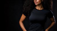 Young African American woman with natural curly hair wearing black t-shirt against dark background, dramatic lighting emphasizes confident pose and natural beauty.