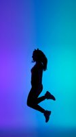 Silhouette of a young woman jumping mid-air against a vibrant purple and teal neon gradient background, expressing joy and energy.