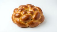 Fresh baked challah bread with golden brown crust and glossy surface isolated on white background for bakery and food design projects.