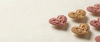 Heart-shaped granola clusters in pink and brown colors scattered on neutral background for healthy breakfast and snack concepts.