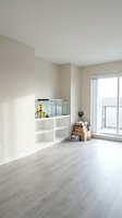 Minimalist apartment interior with white modular shelving unit, light wood flooring, and large window with natural daylight. Suitable for real estate, interior design, and home decor projects.
