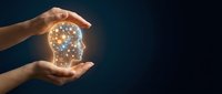 Human hands protecting glowing brain with neural network connections representing artificial intelligence, mental health care, and cognitive protection concept.