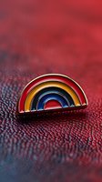 Colorful rainbow enamel pin on red leather texture background with shallow depth of field, macro photography showing fine details and metallic elements.