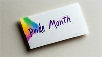 Rainbow gradient business card with Pride Month text in purple handwritten style lettering on white paper against neutral background.