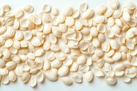 White pumpkin seeds scattered on light background, raw organic pepitas for healthy snacking, cooking ingredients, or nutritional supplements.