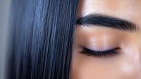 Close up portrait of Asian woman with closed eyes, long straight black hair, and defined eyebrows showing natural makeup look against blurred background.