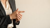 Professional businesswoman in gray suit gesturing with hands during presentation or meeting, corporate communication and leadership concept.