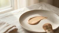 Ceramic bowl with wooden spoon on linen fabric in soft natural light for kitchen styling and culinary photography projects.