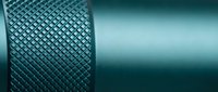Close-up of textured metal cylinder with diamond pattern knurling against smooth surface. Industrial machinery component for manufacturing and engineering.