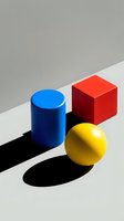 Blue cylinder, red cube, and yellow sphere arranged on divided surface with shadows, representing geometric shapes and abstract composition for design projects.