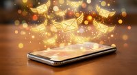 Modern smartphone with glowing email icons and golden light effects floating above screen on wooden surface for digital communication concepts.