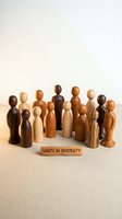 Wooden figurines in various natural tones arranged in a circle with a block reading unity in diversity, symbolizing inclusion, equality, and community cooperation for corporate messaging.