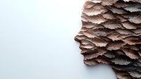Layered profile silhouette created from stacked textured paper in brown and grey tones against white background, showing depth and dimension in contemporary art style.