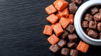 Raw salmon and beef cubes arranged on dark slate background, fresh protein ingredients for pet food or poke bowl preparation, healthy meat portions.